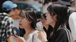 Badan Meteorologi Jepang mengeluarkan peringatan mengenai cuaca panas ekstrem yang kembali melanda sejumlah wilayah pada Selasa, 5 Agustus 2025. Tampak dalam foto, pejalan kaki menggunakan kipas angin genggam mereka di Tokyo pada 5 Agustus 2025. (Kazuhiro NOGI/AFP)