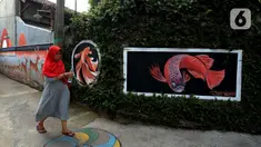 Warga berjalan dekat mural yang menghiasi tembok rumah warga RT 02/RW 07 Kampung Warna-warni, Kelurahan Pengadegan, Jakarta Selatan, Selasa (10/12/2019). Mural di kampung ini dibuat dari dana swadaya warga setempat. (merdeka.com/Imam Buhori)