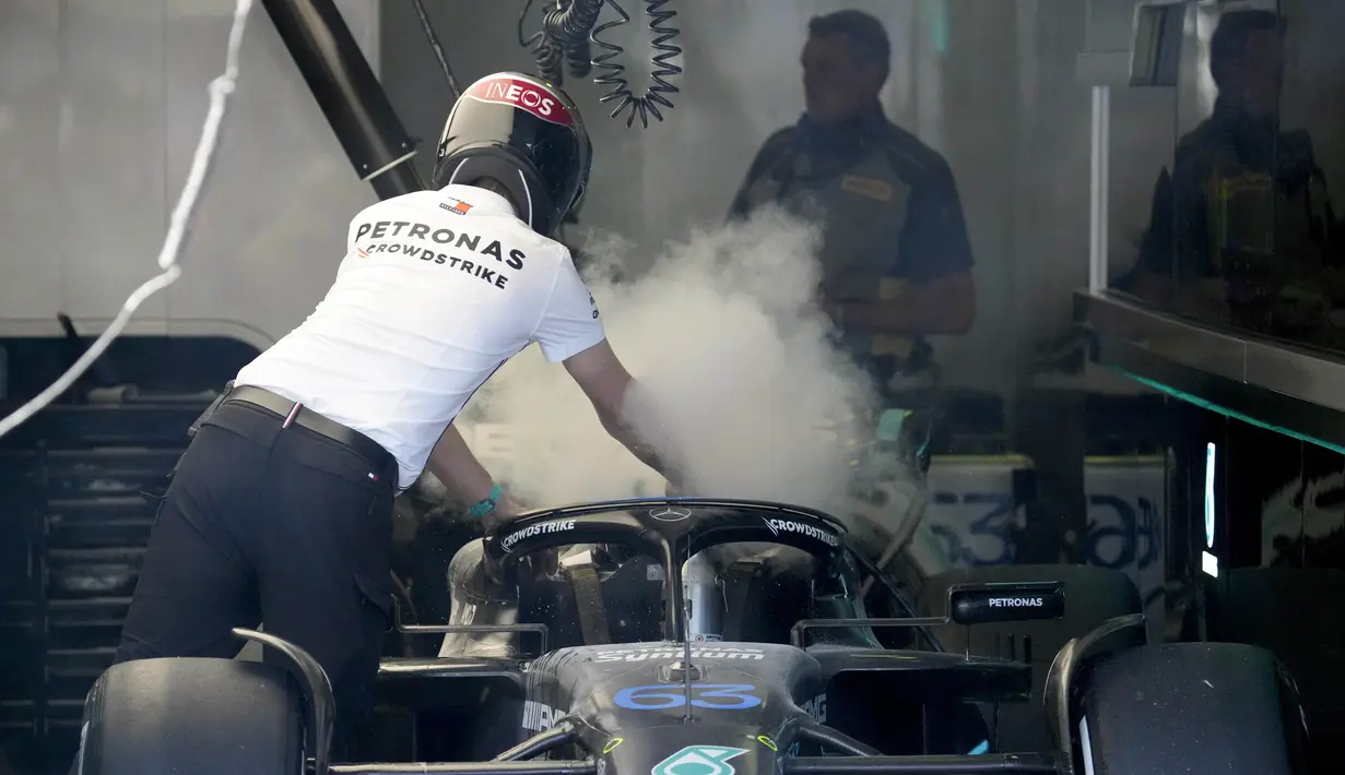 Kondisi mobil dari pembalap Mercedes, George Russell yang terus menerus mengeluarkan asap putih dari bagian mesin saat dibawa oleh mekanik menuju garasi. (AFP/Pool/Simon Baker)