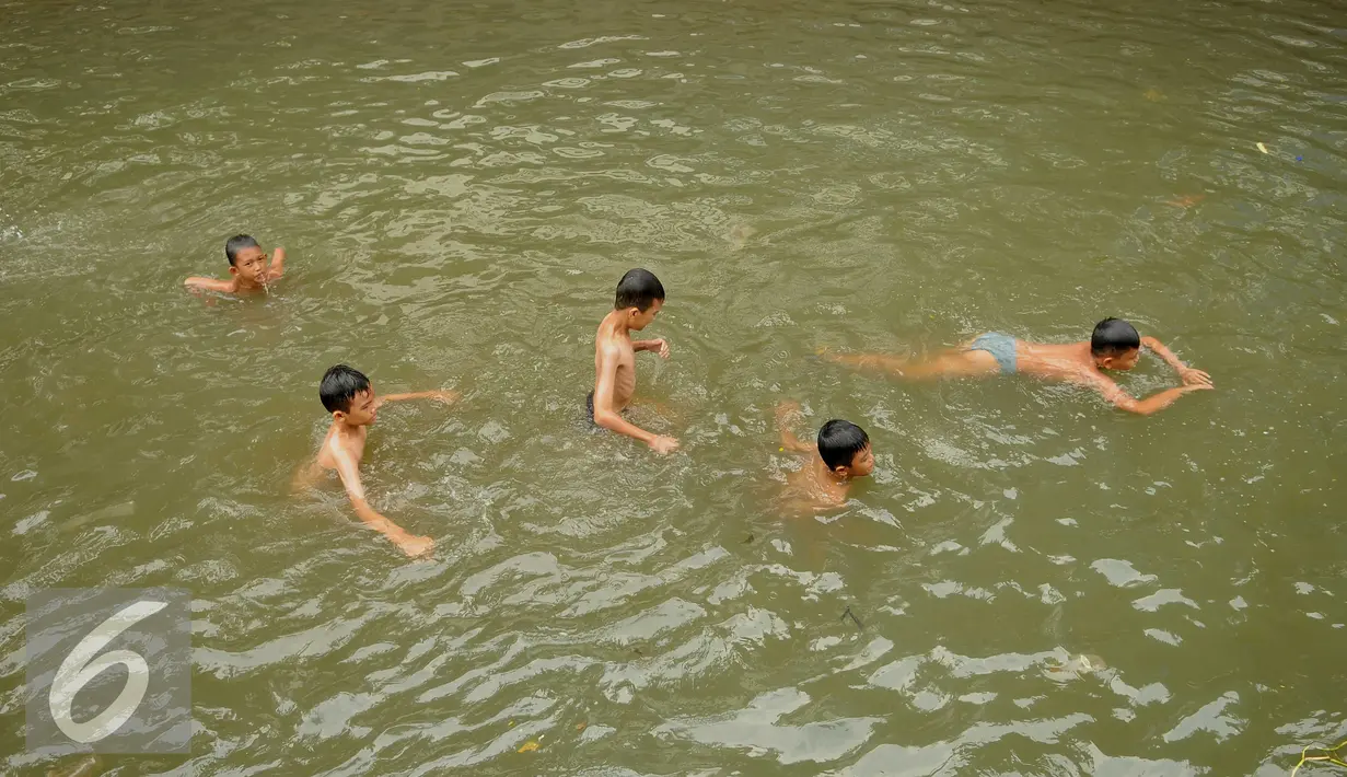 Sejumlah anak berenang di Anak Sungai Ciliwung di Jalan Labu, Kelurahan Mangga Besar sudah mulai membaik, Jakarta, Selasa (17/5). Kondisi air yang mulai jernih dimanfaatkan mereka untuk bermain dan berenang. (Liputan6.com/Gempur M Surya)