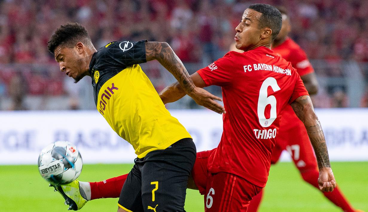 Gelandang Dortmund, Jadon Sancho, berebut bola dengan gelandang Bayern Munchen, Thiago Alcantara, pada laga Piala Super DFL di Stadion Signal Iduna, Dortmund, Sabtu (3/8). Dortmund menang 2-0 atas Munchen. (AFP/Ina Fassbender)
