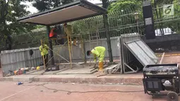 Pekerja menyelesaikan pembuatan halte bus di depan Mesjid Istiqlal, Jakarta, Sabtu (6/1). Pembuatan halte tersebut dilakukan untuk meningkatkan kenyamanan bagi pengguna transportasi umum. (Liputan6.com/Immanuel Antonius)