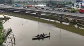 Pengendara sepeda motor menggunakan jasa perahu eretan menyeberangi Sungai Kali Angke di Kecamatan Penjaringan, Jakarta, Rabu (29/5/2024). (merdeka.com/Arie Basuki)