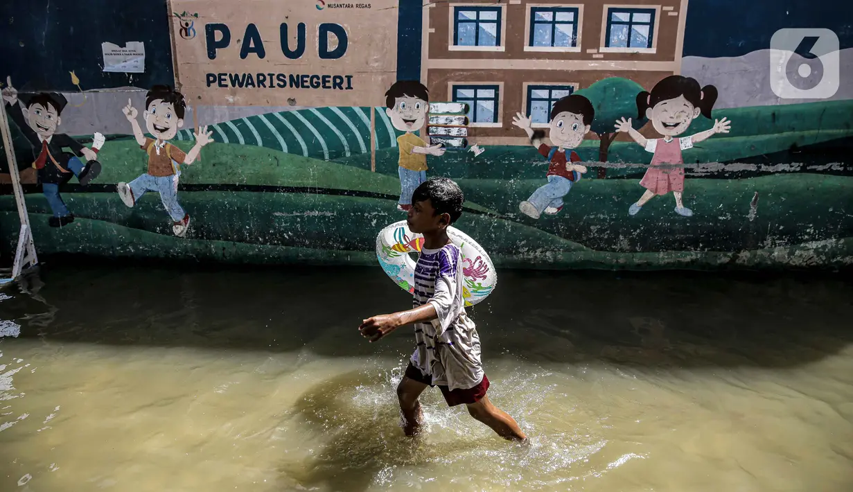 Seorang anak bermain air banjir rob di kawasan Muara Angke, Jakarta, Selasa (9/11/2021). Badan Penanggulangan Bencana Daerah (BPBD) DKI Jakarta memperkirakan puncak musim hujan dan potensi rob di Ibu Kota terjadi pada Januari hingga Februari 2022. (Liputan6.com/Faizal Fanani)