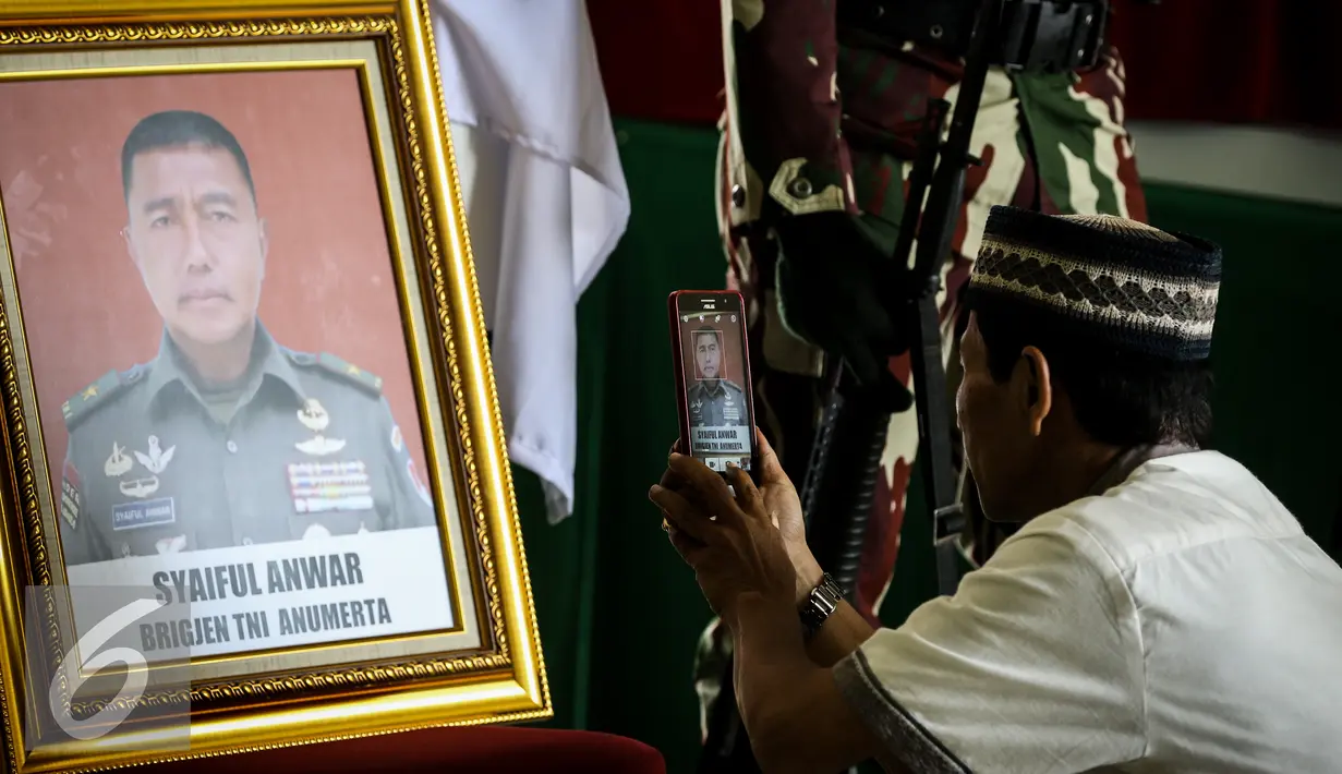 Kerabat memfoto korban jatuhnya Helikopter TNI AD jenis Bell 412 EP di Hanggar Skadron Udara 17 Lanud Halim Perdanakusuma, Jakarta, Selasa (22/3). 13 prajurit TNI tewas akibat kecelakaan helikopter tersebut. (Liputan6.com/Faizal Fanani)
