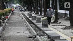 Pejalan kaki melintas saat pekerja menyelesaikan proyek revitalisasi pedestrian di kawasan Jalan Pattimura, Jakarta, Rabu (8/6/2022). Dinas Bina Marga DKI Jakarta merevitalisasi pedestrian dengan memperlebar menjadi tiga meter sehingga cukup luas untuk memberikan kenyamanan para pejalan kaki. (Liputan6.com/Faizal Fanani)