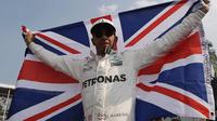 Lewis Hamilton membentangkan bendera negaranya saat merayakan kemenangannya meraih juara dunia F1 untuk yang ke empat kalinya di Autodromo Hermanos Rodrigue, Meksiko (29/10). (AP Photo / Moises Castillo)