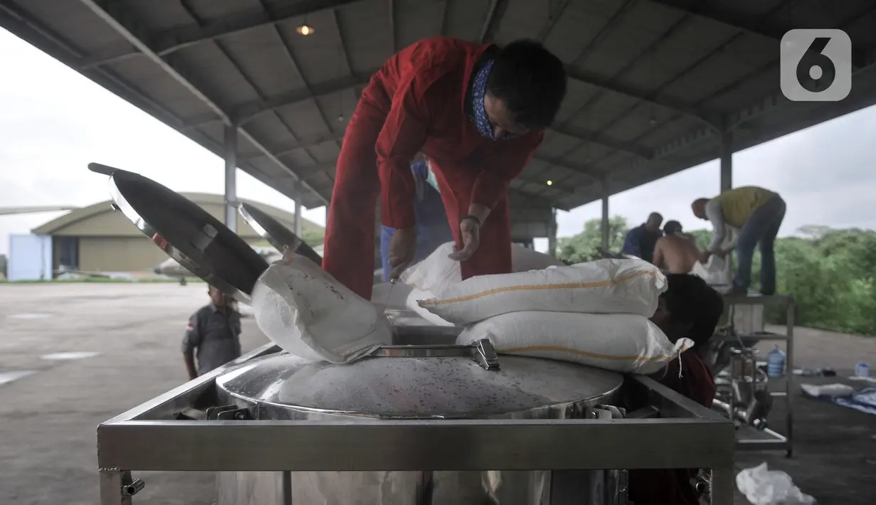 Tim Penabur dari BPPT memasukkan garam ke dalam konsol sebelum dibawa pesawat di Lanud Halim Perdanakusuma, Jakarta (9/1/2020). TNI dan BPPT melakukan operasi TMC dengan menaburkan garam di atas awan kumulonimbus melalui dua pesawat, yakni CN-295 dan Cassa 212-200. (merdeka.com/Iqbal S. Nugroho)