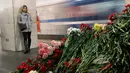 Seorang wanita melihat tumpukan bunga yang diletakkan di dekat lokasi bom meledak di stasiun kereta bawah tanah St. Petersburg, Rusia, Selasa (4/4). Dikabarkan 10 orang meninggal dalam tragedi tersebut. (AP Photo / Dmitri Lovetsky