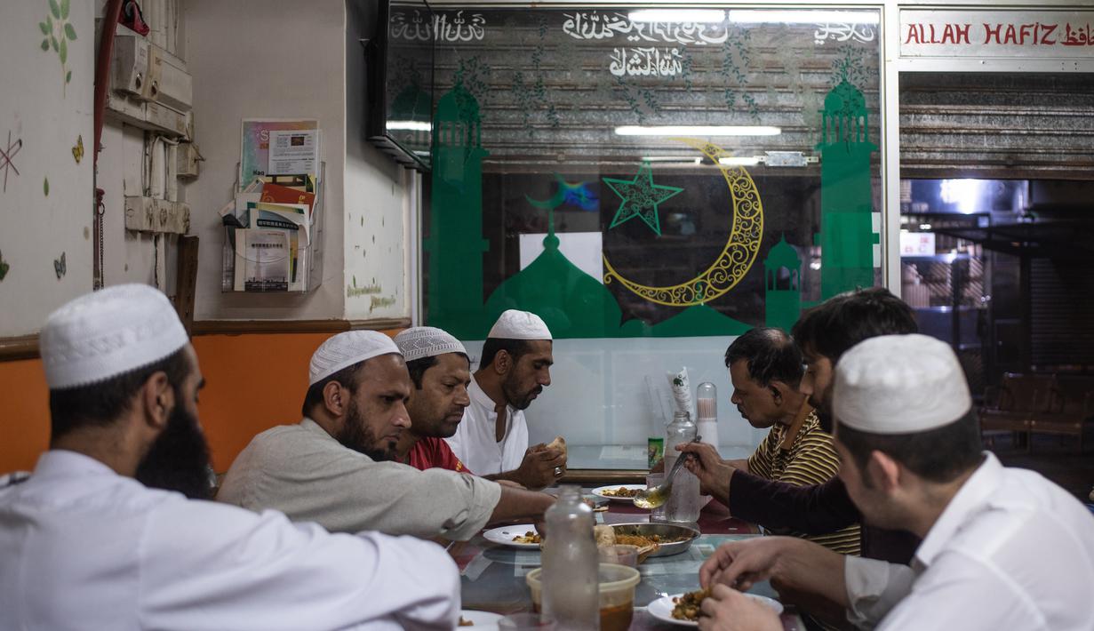 Para imigran Pakistan menikmati makanan sahur sebelum beribadah puasa di distrik Kwai Chung di Hong Kong (25/5/2019). Kwai Chung adalah daerah perkotaan di dalam Kota Baru Tsuen Wan di Wilayah Baru Hong Kong. (AFP Photo/Philip Fong)