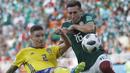Pemain Swedia, Mikael Lustig (kiri) menghalau bola dari kejaran pemain Meksiko, Hector Herrera pada laga grup F Piala Dunia 2018 di Yekaterinburg Arena, Yekaterinburg, Rusia, (27/6/2018).  Swedia menang telak 3-0 atas Meksiko. (AP/Eduardo Verdugo)