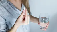 Ilustrasi meminum obat untuk hilangkan rasa sakit. (Sumber foto: Pexels.com).