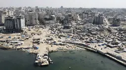 Selama dua tahun terakhir, sejak serangan Israel yang dimulai Oktober 2023, wilayah Gaza berubah menjadi episentrum kehancuran. Tampak dalam foto dari udara yang memperlihatkan tenda-tenda yang menampung pengungsi Palestina di kawasan yang rusak akibat perang di sekitar pelabuhan Kota Gaza pada 20 Oktober 2025, selama gencatan senjata yang dimediasi oleh Amerika Serikat antara Israel dan faksi-faksi Palestina. (Foto oleh AFP)