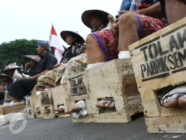 Sejumlah warga Petani Kendeng, Pati, Jawa Tengah menyemen kakinya di depan Istana Negara, Jakarta, Selasa (14 /3). Pada aksi ini di hari kedua ini jumlah petani yang mencor kakinya bertambah menjadi sebelas orang. (Liputan6.com/Helmi Afandi)