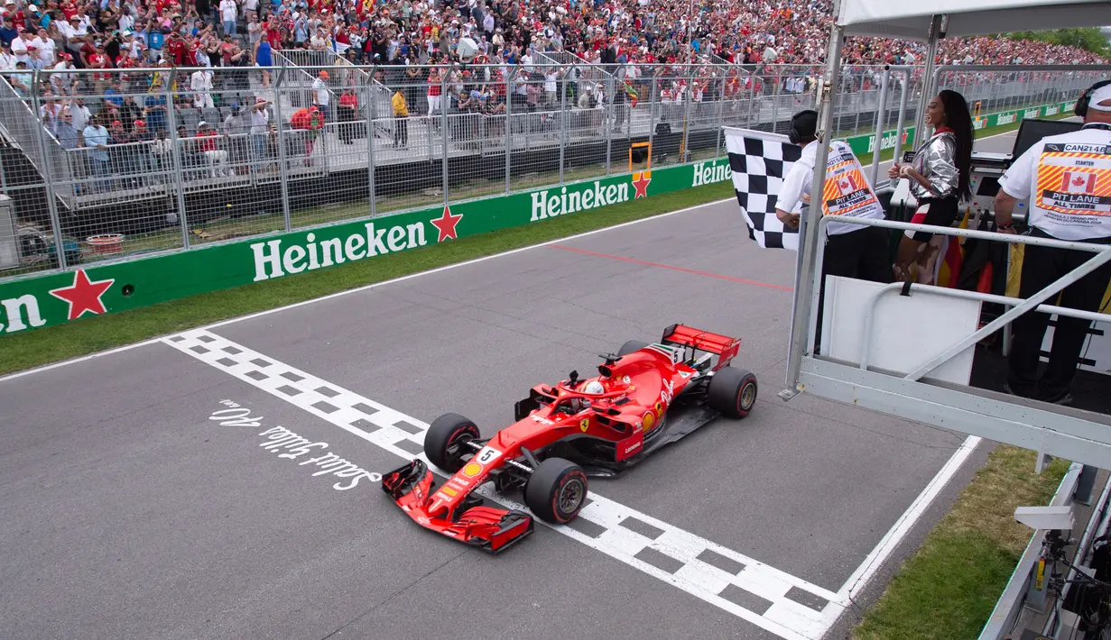 Pembalap Ferrari, Sebastian Vettel melintasi garis finish saat menjuarai F1 GP di Montreal, Kanada, Minggu (10/6). Vettel kini mengoleksi 121 poin unggul satu angka dari Luis Hamilton yang turun ke posisi kedua. (Tom Boland/The Canadian Press via AP)