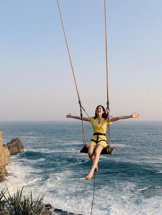 Faradilla Yoshi sangat menyukai traveling seperti saat mengunjungi salah satu pantai di Yogyakarta. Kebahagiaan pun terlihat jelas dari raut wajah perempuan berusia 27 tahun saat menaiki ayunan di pinggir pantai. (Liputan6.com/IG/@faradillayoshi)