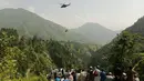 Orang-orang menyaksikan seorang tentara terjun dari helikopter selama misi penyelamatan untuk menyelamatkan para siswa yang terjebak di keeta gantung di desa Pashto di provinsi pegunungan Khyber Pakhtunkhwa, pada 22 Agustus 2023. (AFP)
