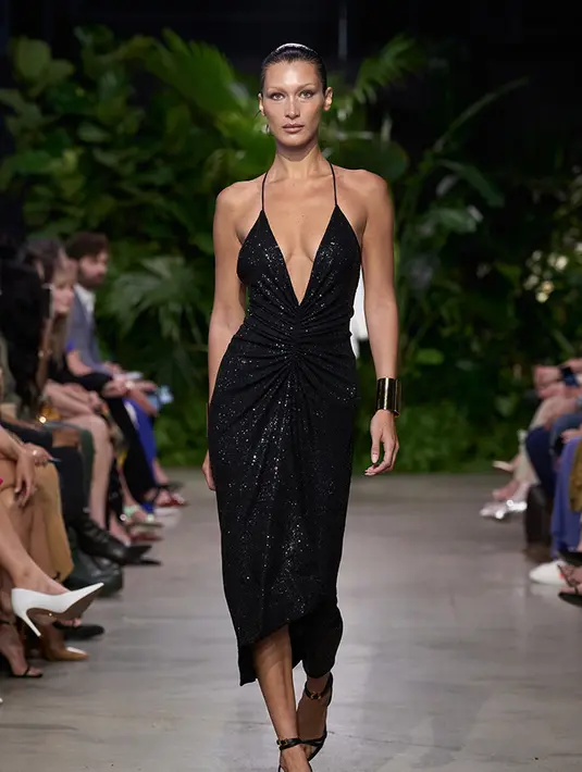 Bella Hadid menjadi salah satu model yang memeragakan koleksi Micheal Kores di runway berkonsep keindahan kota dengan tanaman hijau yang terinspirasi oleh resort getaway yang memadukan antara urbanitas dan alam. Michael Kors