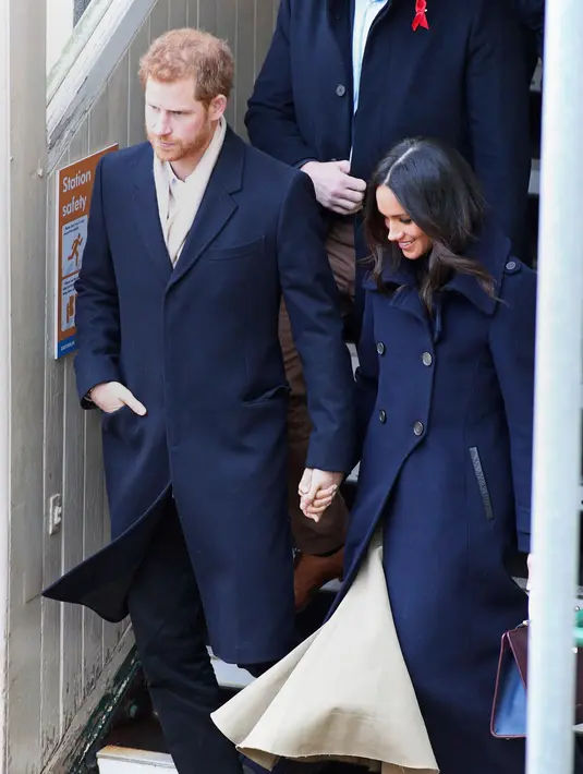 Pangeran Harry dan tunangannya, Meghan Markle menghadiri acara amal untuk memperingati Hari AIDS Sedunia di Nottingham, Jumat (1/12). Pangeran Harry mengenakan syal krem yang senada dengan warna rok maksi Meghan Markle. (Steve Parsons/PA via AP)