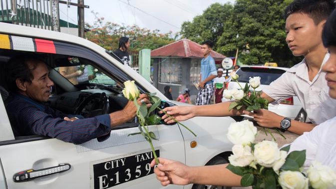 Umat Buddha Myanmar memberikan mawar putih kepada umat Islam yang akan melaksanakan salat Id pada perayaaan Idul Fitri di kota Than Lyin, Yangon, Rabu (5/6/2019). Tindakan itu dilakukan beberapa minggu setelah kelompok garis keras berusaha menghapuskan doa selama bulan Ramadhan. (Sai Aung MAIN/AFP)