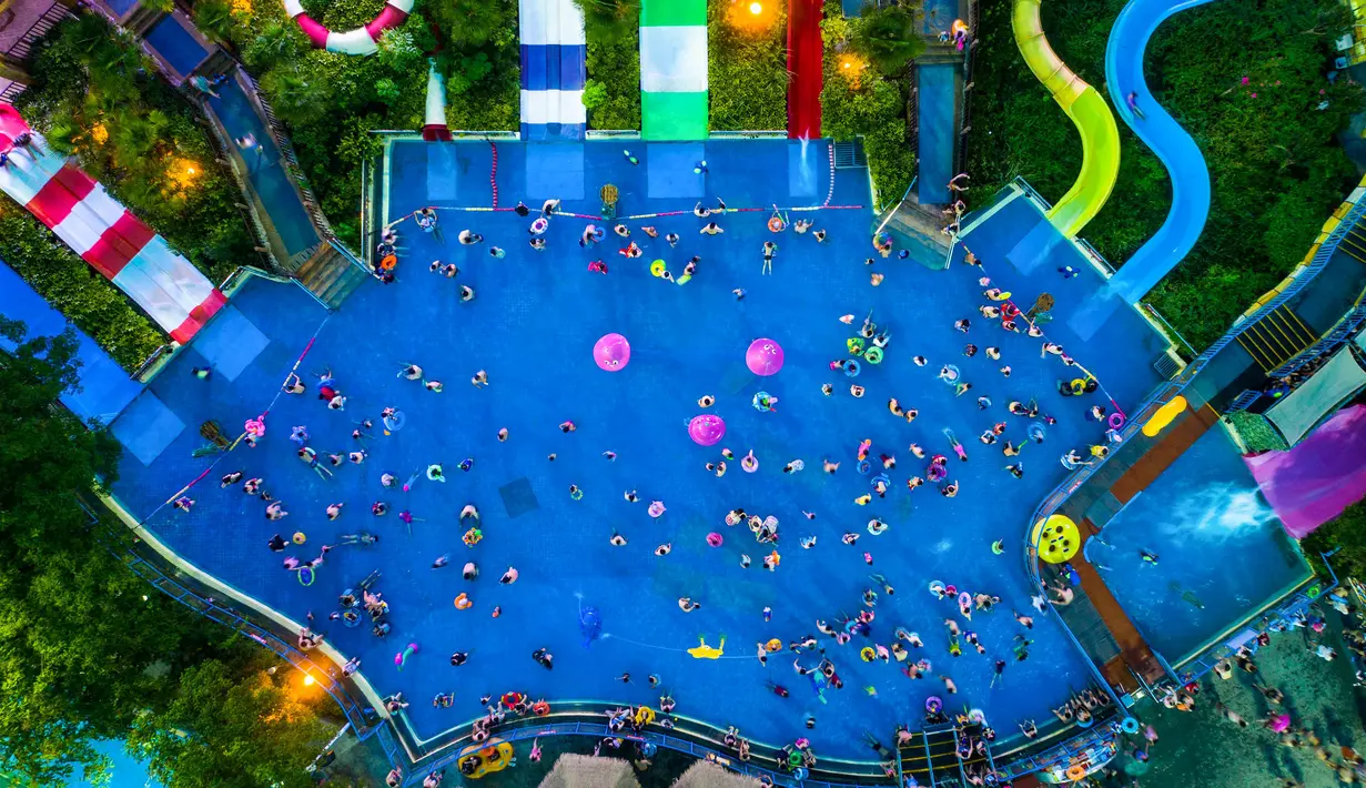 Pengunjung bersantai sambil mendinginkan diri di kolam renang di Wuhan rovinsi Hubei, China pada 27 Juli 2019. Cuaca yang cukup panas membuat mereka berbondong-bondong menyesaki kolam renang. (Photo by - / AFP)
