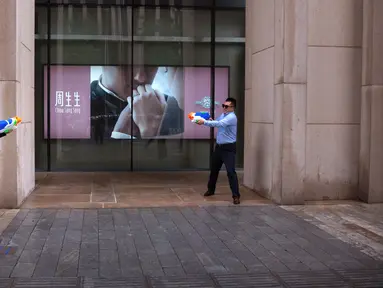 Pekerja kantor pria dan wanita bermain senjata air di luar kantor, Beijing, (13/7). Karyawan di China terkadang menghabiskan waktu berjam-jam di tempat kerja dan beralih bermain dengan ide kreatif untuk menghilangkan stres. (AP Photo/Mark Schiefelbein)