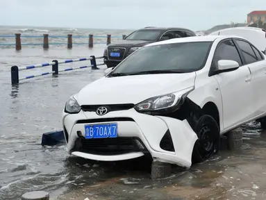 Sebuah mobil rusak setelah dihantam ombak yang disebabkan Topan Yagi di sepanjang pantai laut di Qingdao di provinsi Shandong timur China (13/8). Lebih dari 200.000 warga mengungsi saat topan mencapai daratan pantai timur. (AFP Photo)