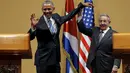 Presiden Kuba Raul Castro mengangkat tangan Presiden AS Barack Obama usai konferensi pers di Istana Revolusi, Havana, Senin (21/3). Obama menjadi presiden pertama AS yang berkunjung ke negara komunis itu sejak 88 tahun terakhir. (REUTERS/Carlos Barria)