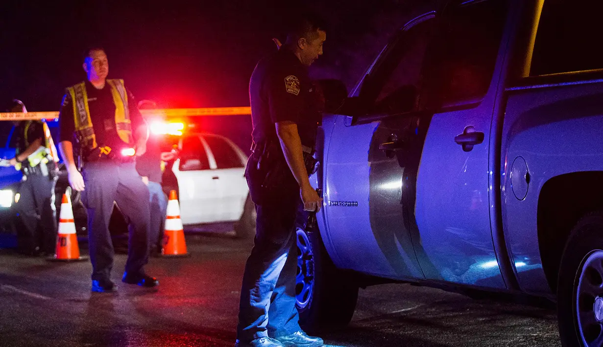 Seorang petugas polisi Austin berbincang dengan rekannya di dekat daerah ledakan di Austin, Texas (18/3). Area di sekitar lokasi ledakan telah diblokir dan otoritas mewawancarai tetangga dan mencari saksi. (Nick Wagner / Austin American-Statesman via AP)