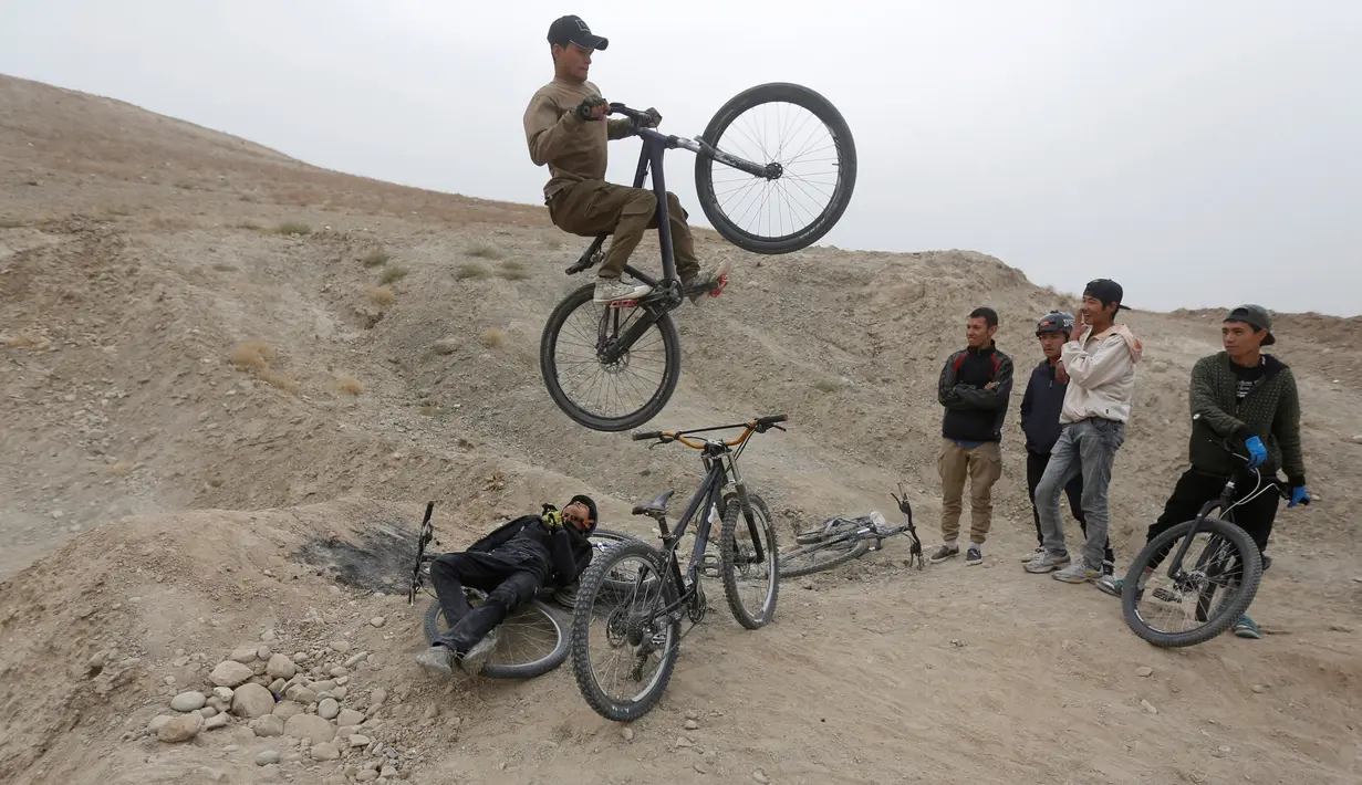 Aksi pemuda Afganistan, melakukan lompatan tinggi disaksikan teman-temannya menggunakan sepeda Dirt Jump (DJ) di Kabul, Afghanistan (20/11). Jenis Dirt Jump ini memiliki fungsi yang mirip dengan BMX .(Reuters/Omar Sobhani)