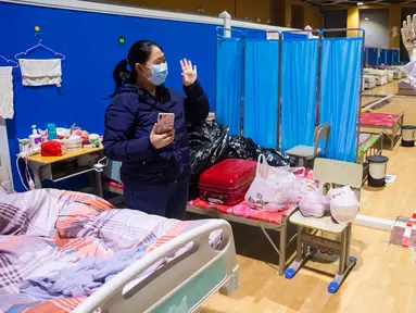 Pasien virus corona atau COVID-19 Ying (kiri) melambaikan tangan kepada petugas medis Cao Jinglei di sebuah rumah sakit sementara di Wuhan, China, Senin (9/3/2020). China menutup semua rumah sakit sementara yang dibuat untuk menangani virus corona di Kota Wuhan. (Xinhua/Shen Bohan)