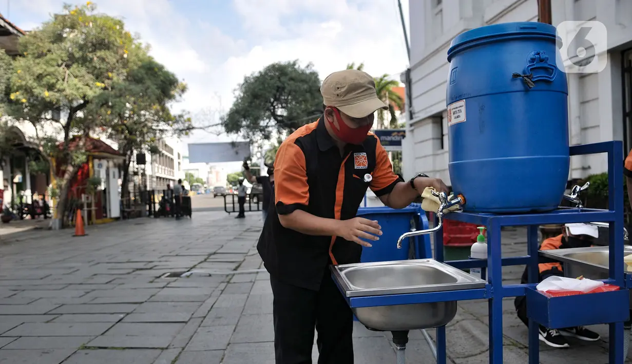 Petugas menyiapkan fasilitas cuci tangan yang disediakan di tiap pintu masuk kompleks wisata Kota Tua, Jakarta, Selasa (2/6/2020). Jelang berakhirnya PSBB di Jakarta, pengelola Kota Tua menyiapkan protokol kesehatan new normal bagi pengunjung. (merdeka.com/Iqbal S. Nugroho)
