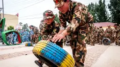 Sejumlah anak-anak mendorong ban saat mensimulasikan latihan militer di sebuah taman kanak-kanak di provinsi Henan, China (30/5). Latihan militer ini dilakukan untuk menjelang Hari Anak Internasional yang jatuh pada 1 Juni. (AFP)