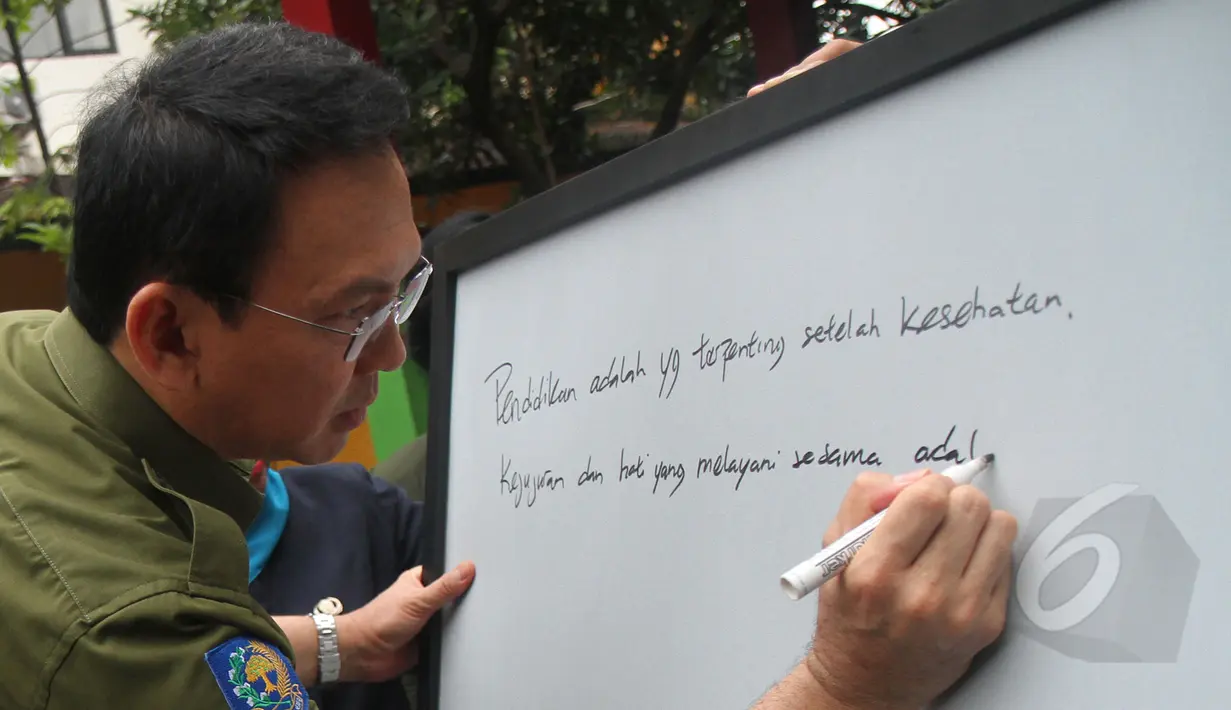Gubernur DKI Basuki 'Ahok' Tjahaja Purnama menuliskan pesan di sebuah papan tulis saat meninjau hari pertama pelaksanaan ujian nasional (UN) di SMKN 27 Jakarta, Senin (13/4/2015). (Liputan6.com/Herman Zakharia)