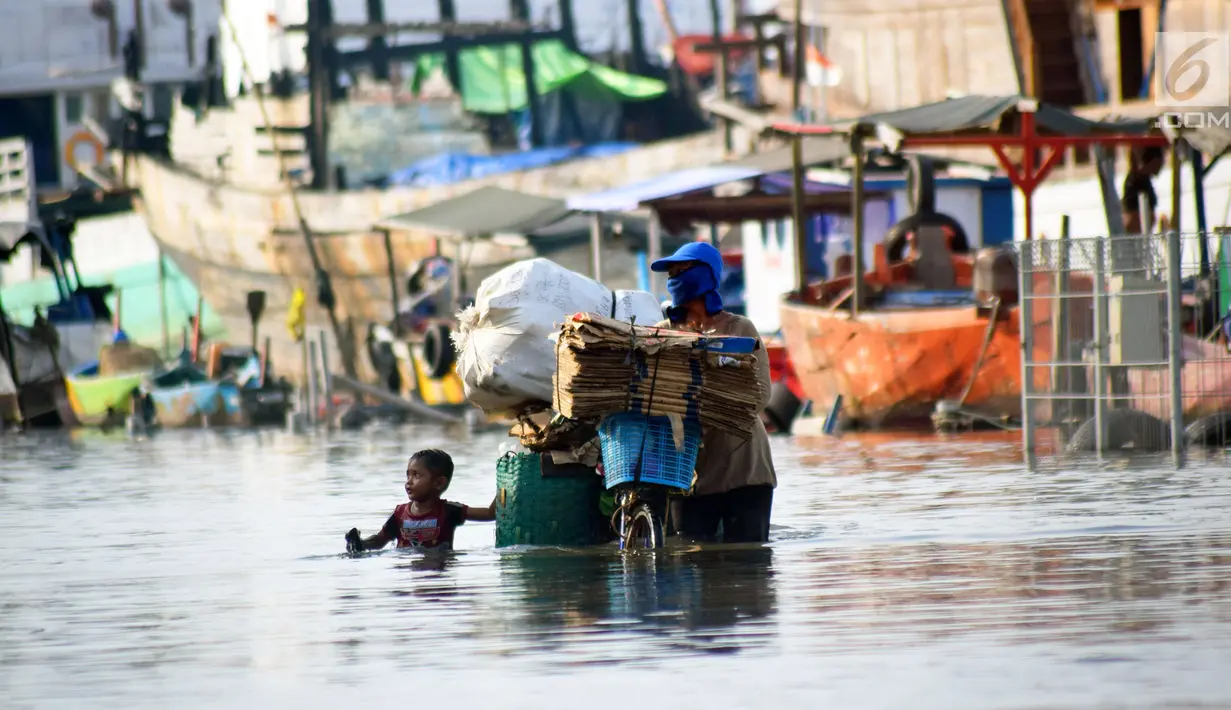 Warga membawa sepedanya melintasi banjir rob di jalan Yos Sudarso Semarang di kawasan Pelabuhan Tanjung Emas (24/4). Banjir akibat pasang air laut masih terjadi di sejumlah titik kota Semarang.  (Liputan6.com/Gholib)