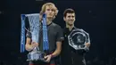 Petenis Jerman, Alexander Zverev memegang trofi pemenang dan Novak Djokovic dari Serbia memegang trofi runner-up setelah laga puncak ATP Finals 2018 di O2 Arena, London, Senin (19/11). (AP/Tim Ireland)