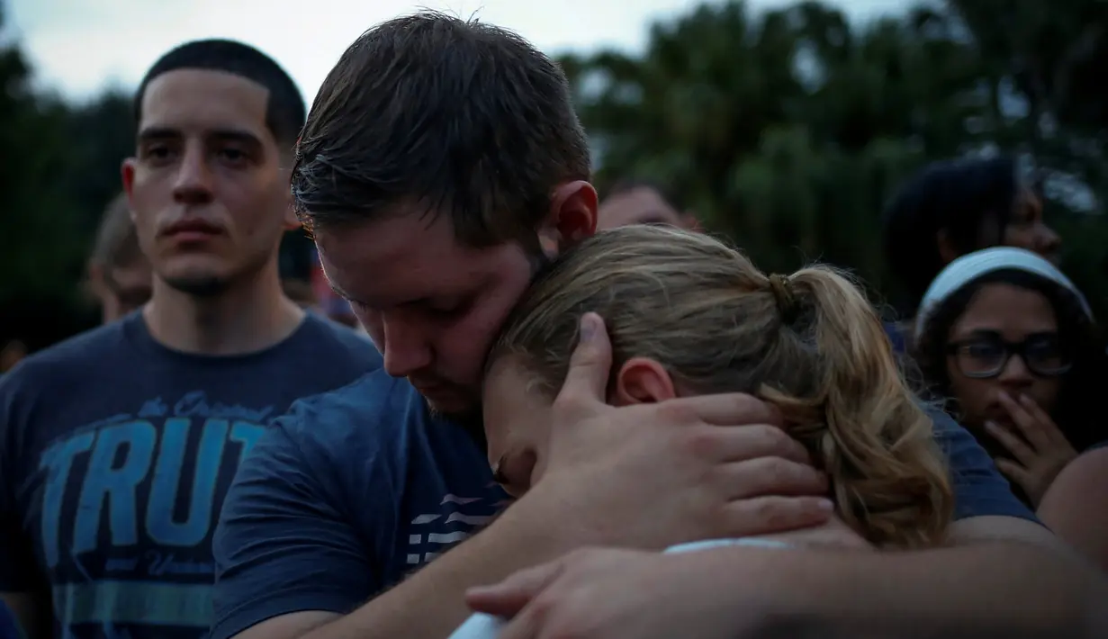 Dua orang berpelukan dalam peringatan untuk korban penembakan di Pulse, klub malam khusus kaum gay di Orlando, Florida, AS, Minggu (12/6). 50 orang tewas dan 53 terluka akibat penembakan yang dilakukan Omar Saddiqui Mateen. (REUTERS/Adrees Latif)
