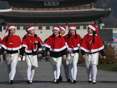 Anak-anak Korea Selatan mengenakan pakaian Santa Claus berjalan di depan Istana Gyeongbokgung, Seoul, Jumat (30/11). Anak-anak tersebut bersiap meluncurkan kampanye penggalangan dana akhir tahun dari The Salvation Army. (Jung Yeon-je/AFP)