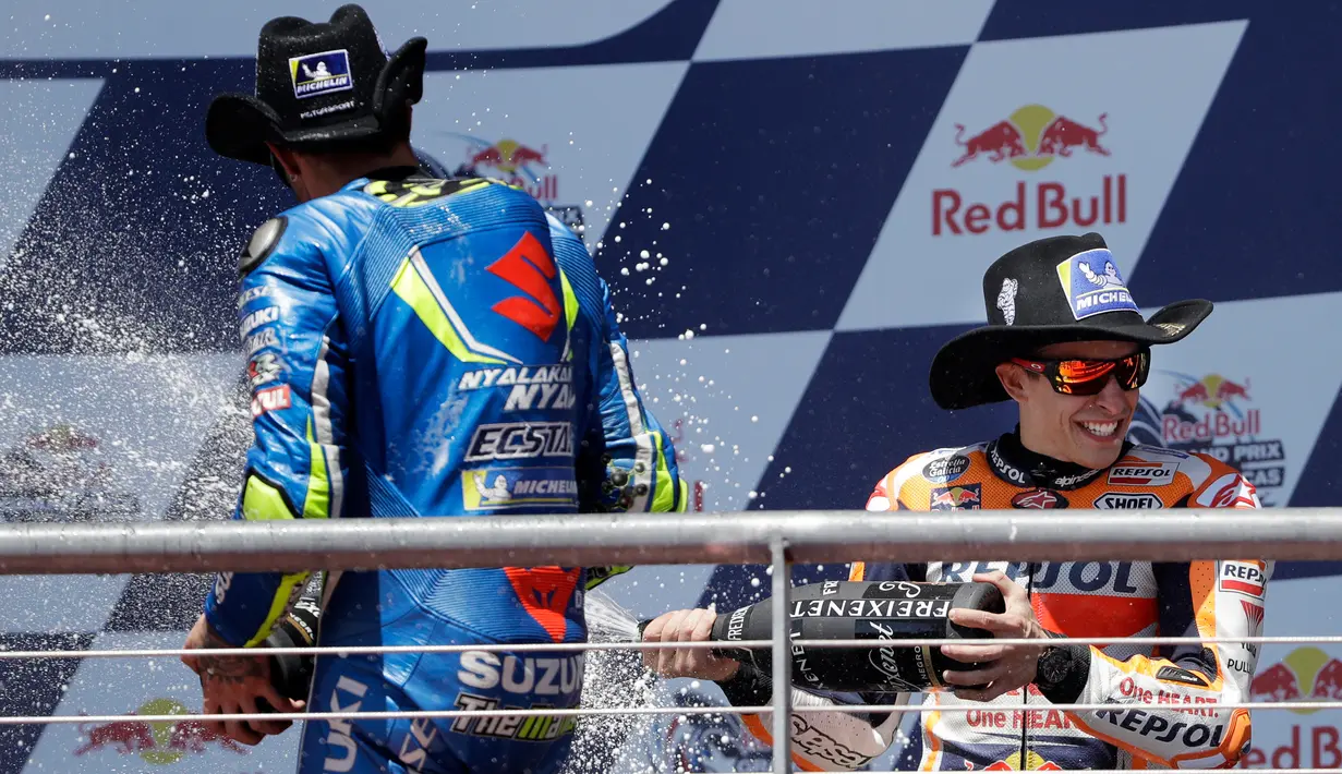 Juara MotoGP Amerika, pembalap Repsol Honda, Marc Marquez dan pembalap Suzuki Ecsta, Andrea Iannone saling menyemprotkan sampanye saat berselebrasi di atas podium Circuit of the Americas (COTA), Austin, Minggu (22/4). (AP/Eric Gay)