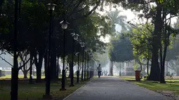 Seorang pria berjalan menikmati suasana Taman Viharamahadevi di Kolombo, Sri Lanka (3/1). Taman ini dibangun selama pemerintahan Britania di Sri Lanka, dan awalnya bernama "Taman Victoria" setelah Ratu Victoria.  (AFP Photo/Lakruwan Wanniarachchi)