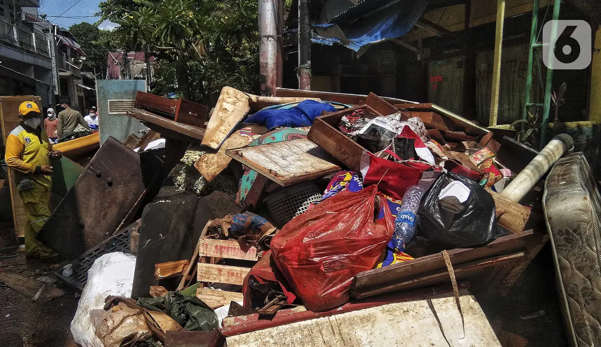 Petugas membersihkan sampah sisa banjir di Kebalen, Jakarta, Minggu (21/2/2021). Banjir yang terjadi kemarin karena curah hujan yang tinggi meninggalkan sampah di rumah warga. (Liputan6.com/Johan Tallo)
