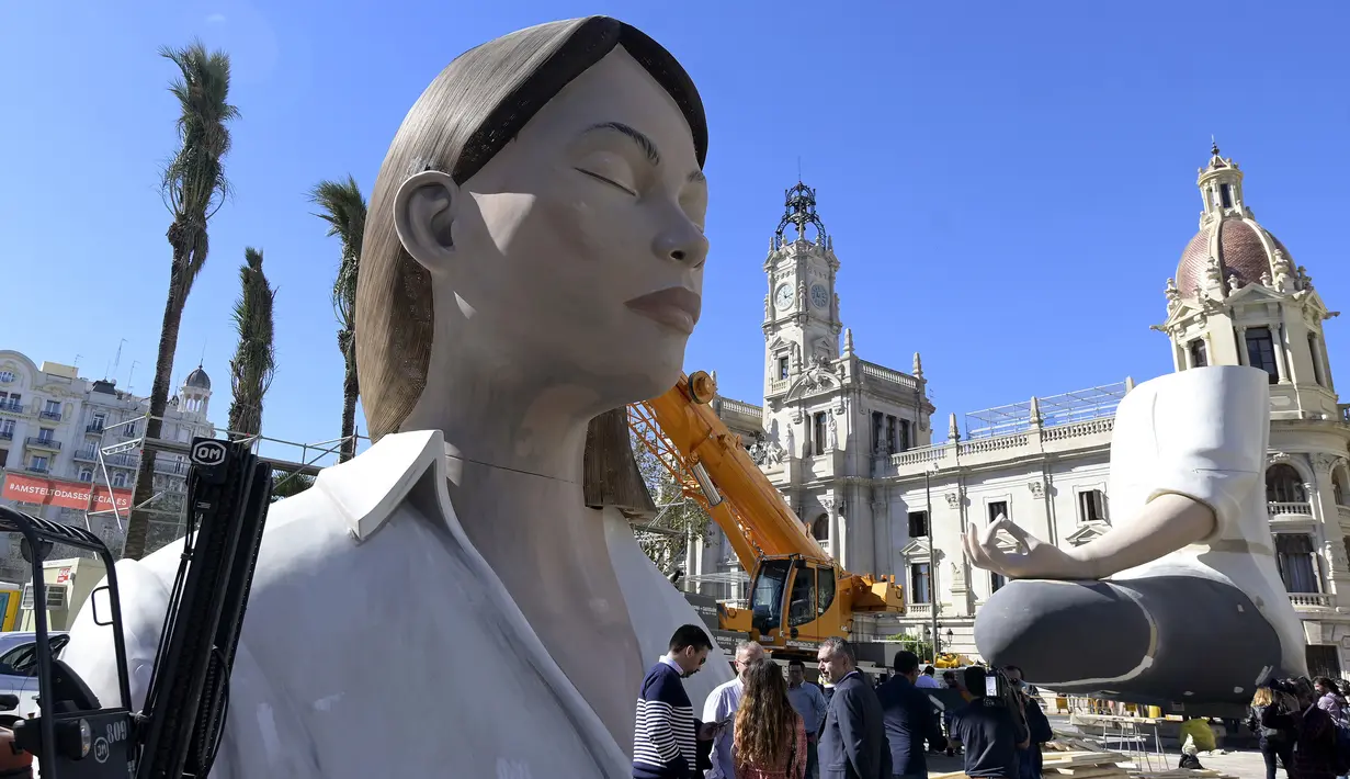 Patung raksasa yang akan ditampilkan di festival Las Fallas atau festival api terlihat sebelum dipasangkan masker di Valencia, Spanyol, Rabu (11/3/2020). Festival Fallas yang akan berlangsung pada 13 Maret telah dibatalkan karena wabah coronavirus. (AFP/Jose Jordan)