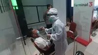 Petugas melakukan tes swab antigen secara acak terhadap penumpang pesawat di Terminal 3 Bandara Soekarno-Hatta (Soetta) saat arus balik Lebaran 2021. (Liputan6.com/Pramita Tristiawati)