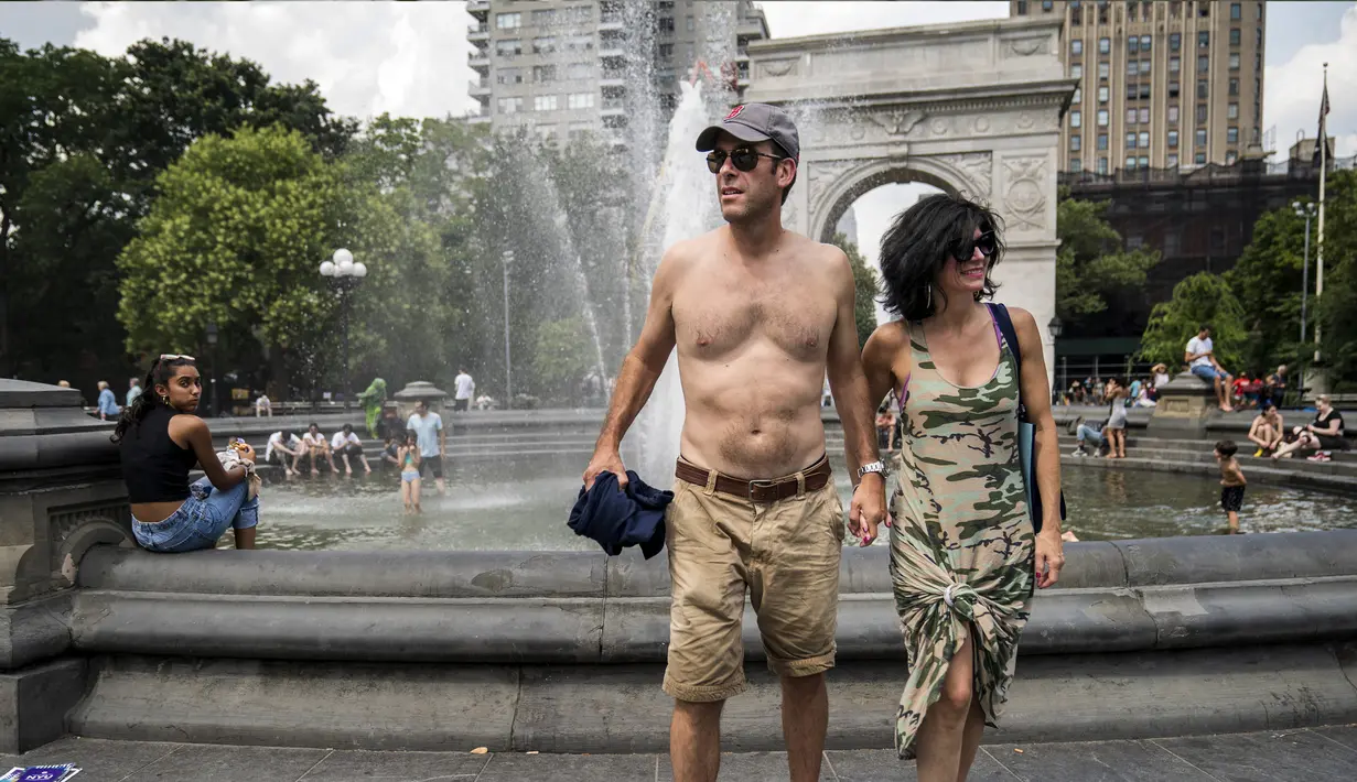 <p>Sejumlah warga mendinginkan tubuhnya di dekat air mancur saat siang hari yang panas di Washington Square Park di New York City (17/7/2019). Panas terik bergerak ke daerah Kota New York, dengan suhu yang diperkirakan akan mencapai 100 derajat pada akhir pekan ini. (AFP Photo/Drew Angerer)</p>