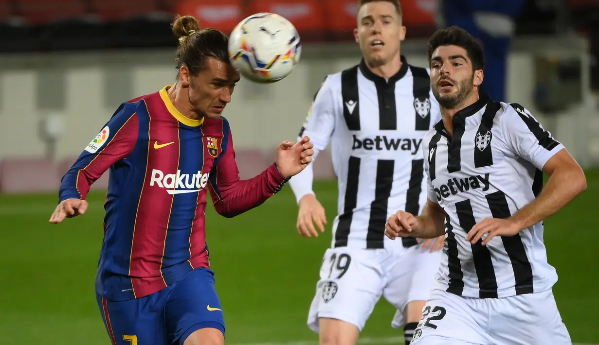 Penyerang Barcelona, Antoine Griezmann, menyundul bola saat melawan Levante pada laga Liga Spanyol di Stadion Camp Nou, Senin (14/12/2020). Barcelona menang dengan skor 1-0. (AFP/Lluis Gene)