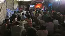 Sejumlah orang menonton film di bioskop darurat yang terletak di bawah jembatan di kuartal tua Delhi, India (25/5). Bioskop ini menampilkan berbagai film dan musik India dengan menggunakan sebuah televisi. (REUTERS/Cathal McNaughton)