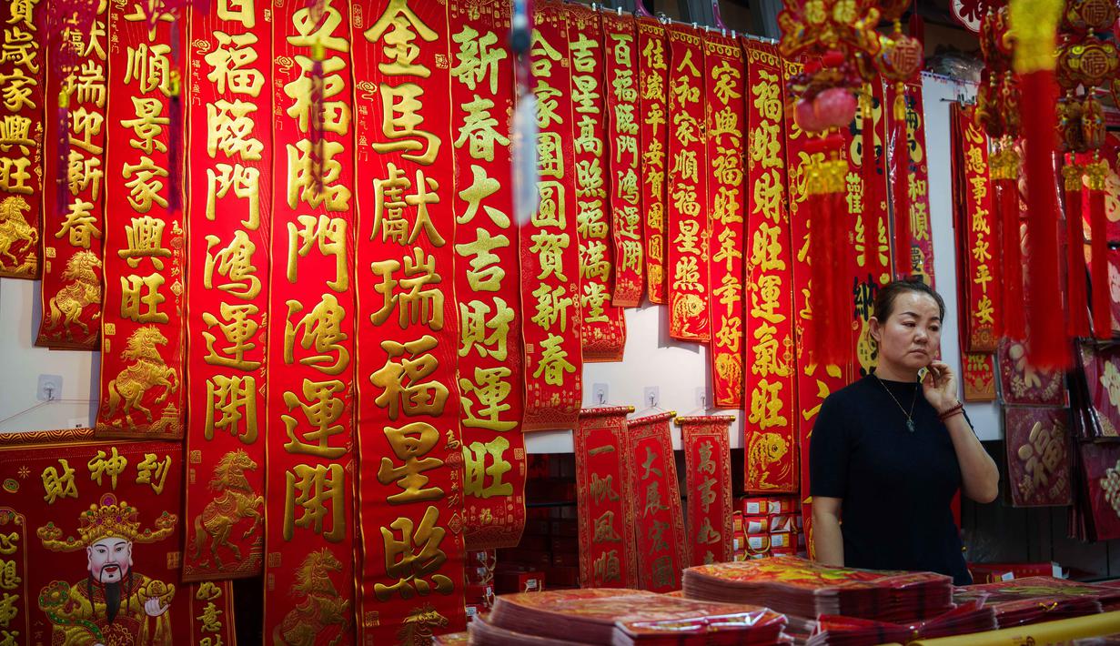 Di China, perayaan Imlek akan berlangsung selama 15 hari. Perayaan Tahun Baru Imlek juga dikenal sebagai Chunjie atau Festival Musim Semi. Tampak dalam foto, seorang penjual menunggu pelanggan di sebuah kios yang menjual bait-bait dan dekorasi Tahun Baru Imlek di sebuah pasar di Beijing, China, Rabu 4 Februari 2026. (AP Photo/Vincent Thian)