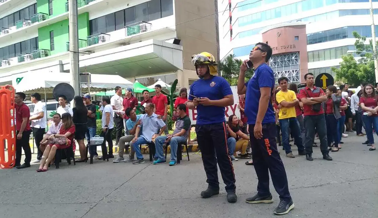 Pegawai kantor berkumpul di luar gedung setelah gempa bumi dahsyat  di Kota Davao, Filipina (29/10/2019). Lokasi gempa berada dekat Kota Kisante dan kurang dari 100 kilometer (60 mil) dari Kota Davao. Pada kedalaman Sekitar 50 kilometer (30 mil). (AP Photo)