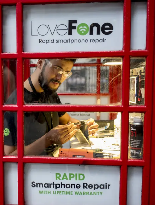 Fouad Choaibi sedang mereparasi ponsel didalam kotak telepon merah di Southhampton Row, London (20/10). Kotak telepon umum merah klasik di Inggris ini dialihfungsikan untuk berbagai jenis kegunaan baru. (AFP Photo/Tolga Akmen)