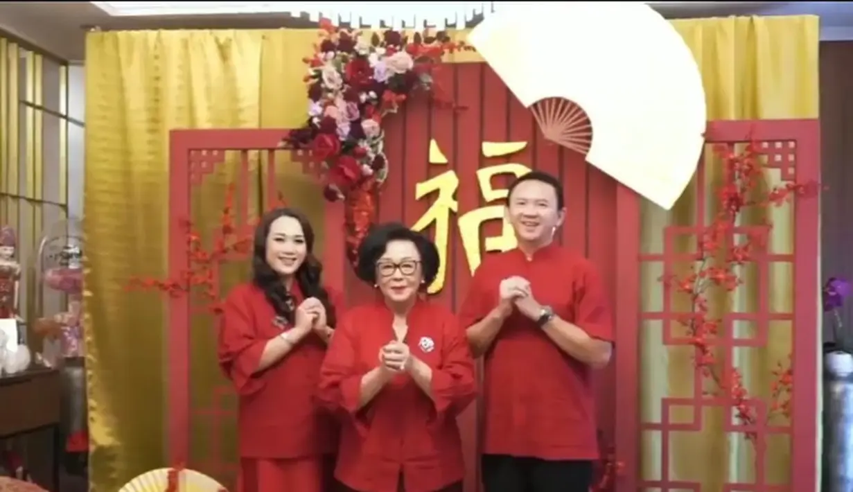 Bersama Puput sang istri, Ahok kompak berbusana merah, dengan latar foto khas imlek.